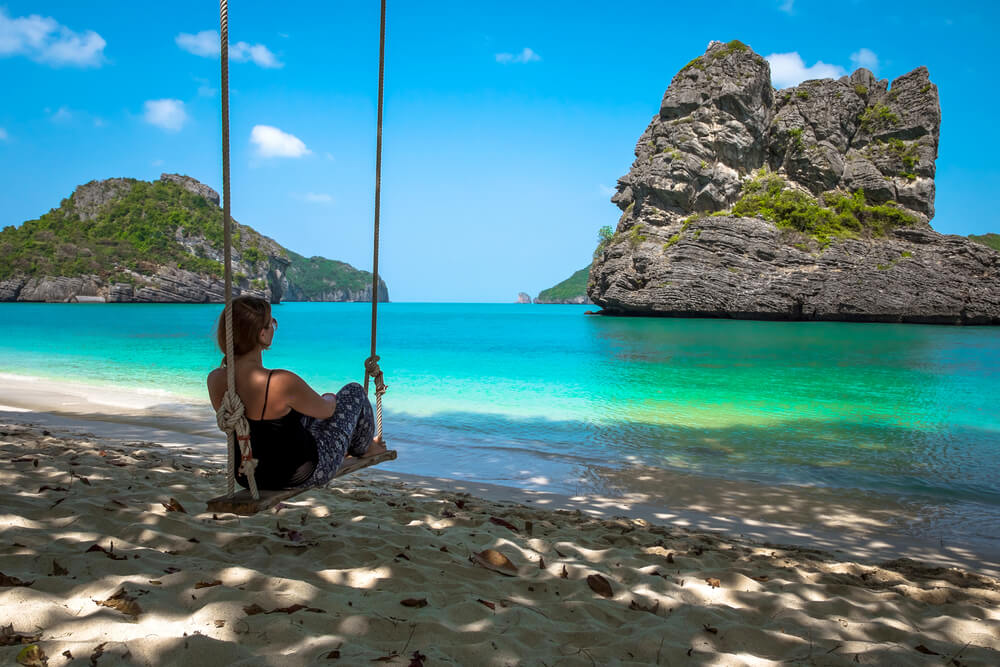 A young girl is meditating on the swing. Beautiful landscape Mu Ko Ang Thong National Marine Park in Thailand. Asia.