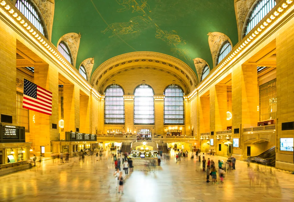 Interior of Grand Central Terminal in New York City, featuring grand hall, arched windows, iconic clock and celestial ceiling mural