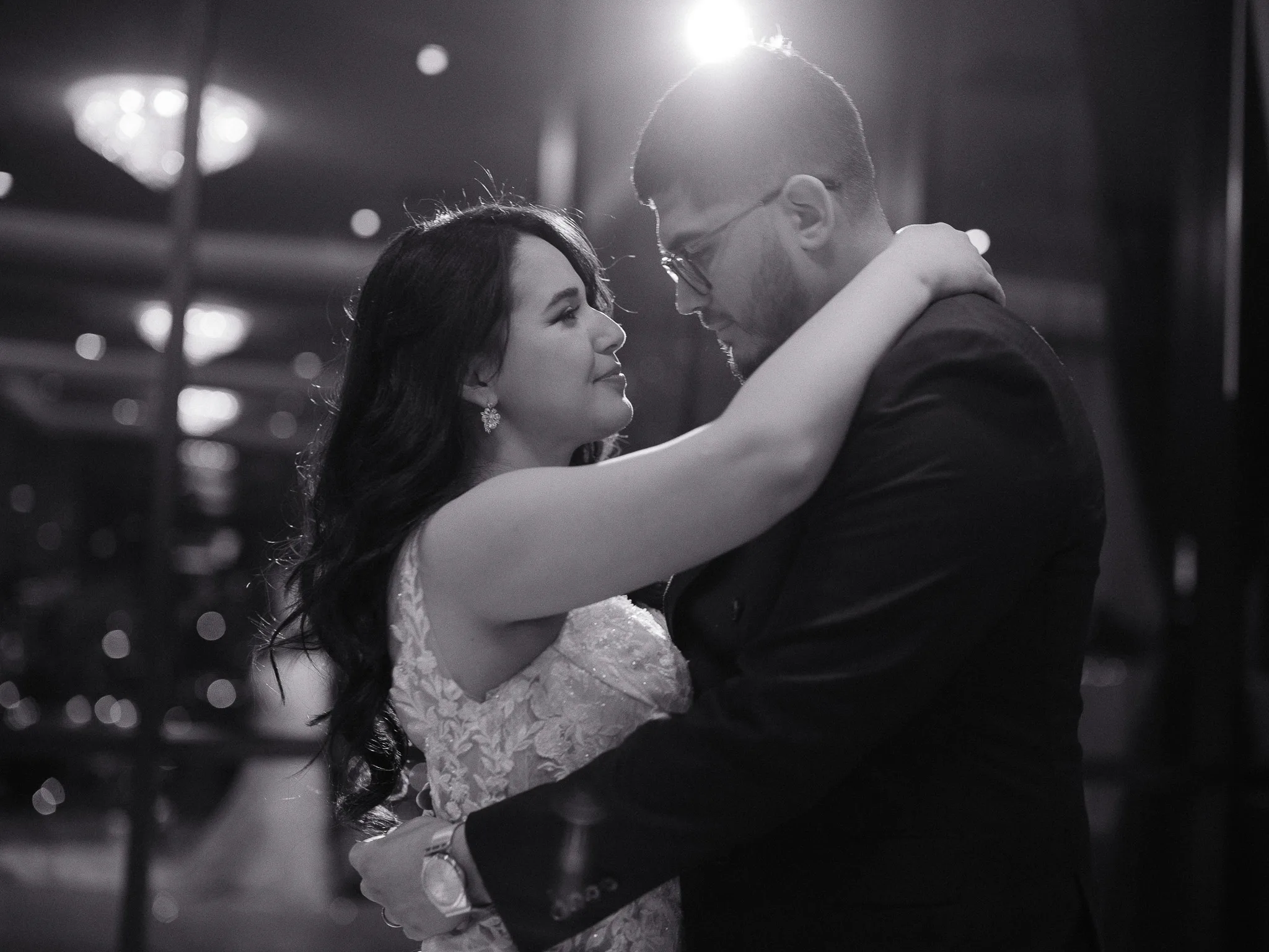 Wide editorial portrait from a wedding day in Astoria — couple framed by the venue's grand window.