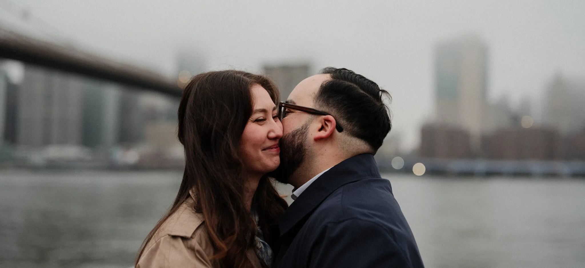 Couple walking across the Brooklyn Bridge at dawn