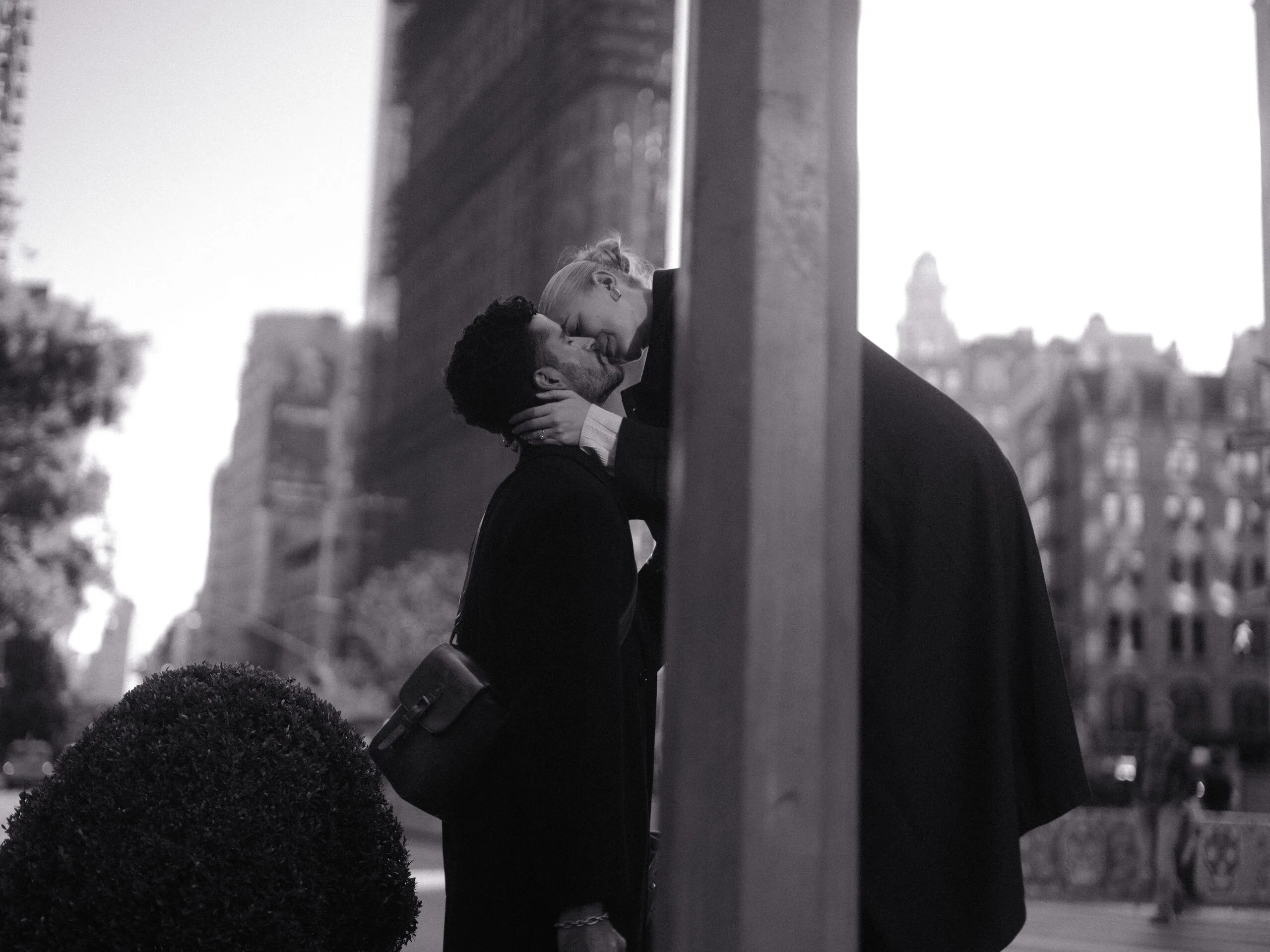 At the top of the subway stairs, the couple in a kiss under an N/Q sign.