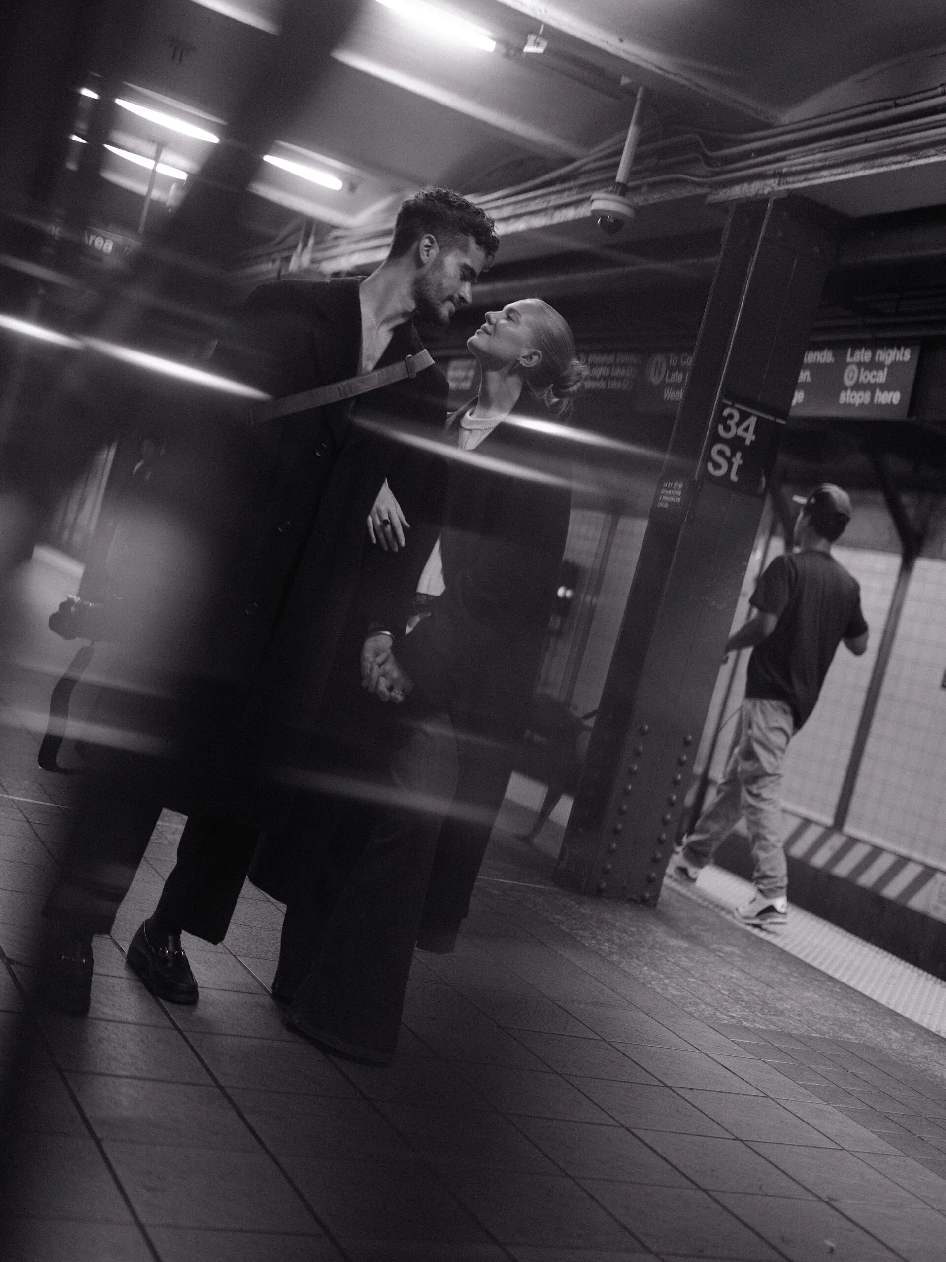 Blurred couple walks past park benches, pigeons rising.