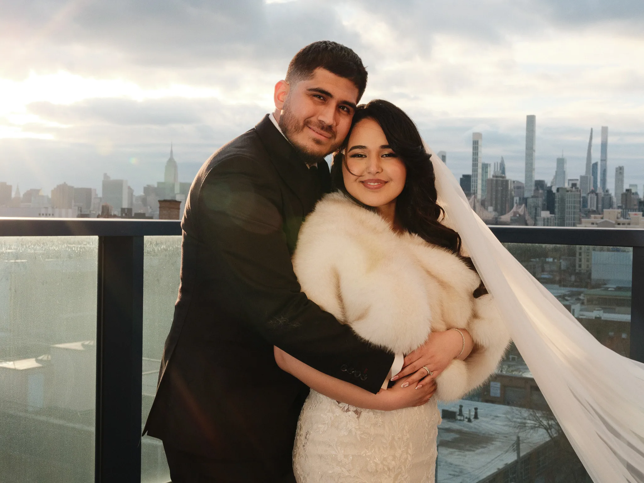 A couple on a Manhattan rooftop at sunset, the skyline behind them.