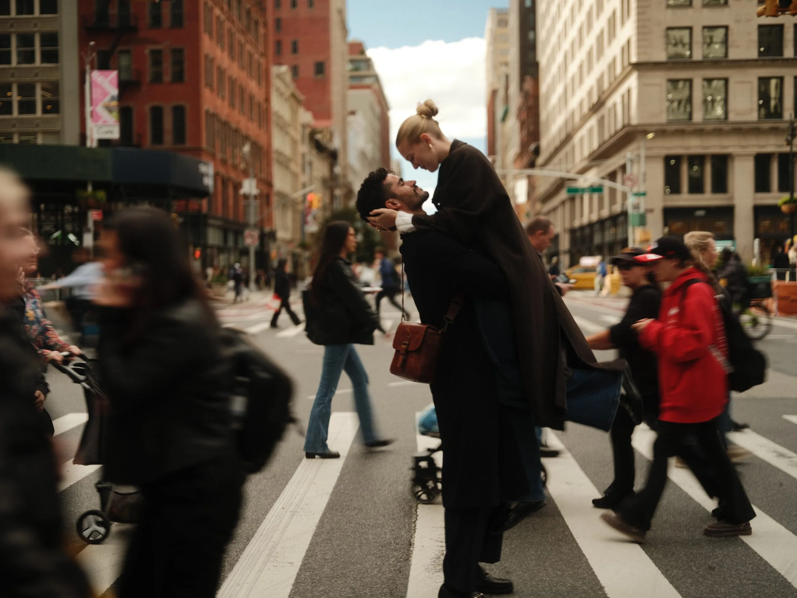 A couple reach for each other crossing Fifth Avenue.