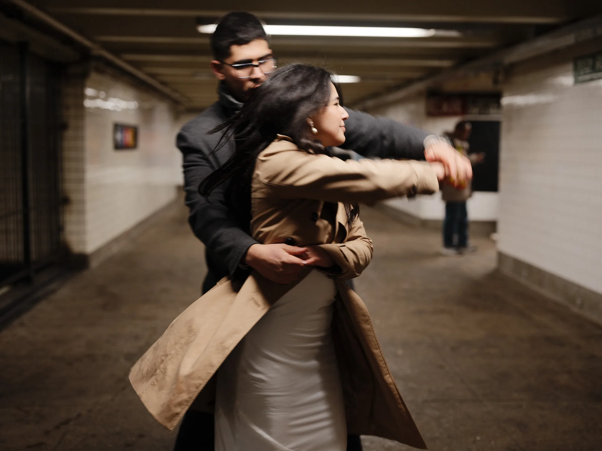 Subway stairs, an Agent-available sign — the couple paused at the bottom, hand to face.