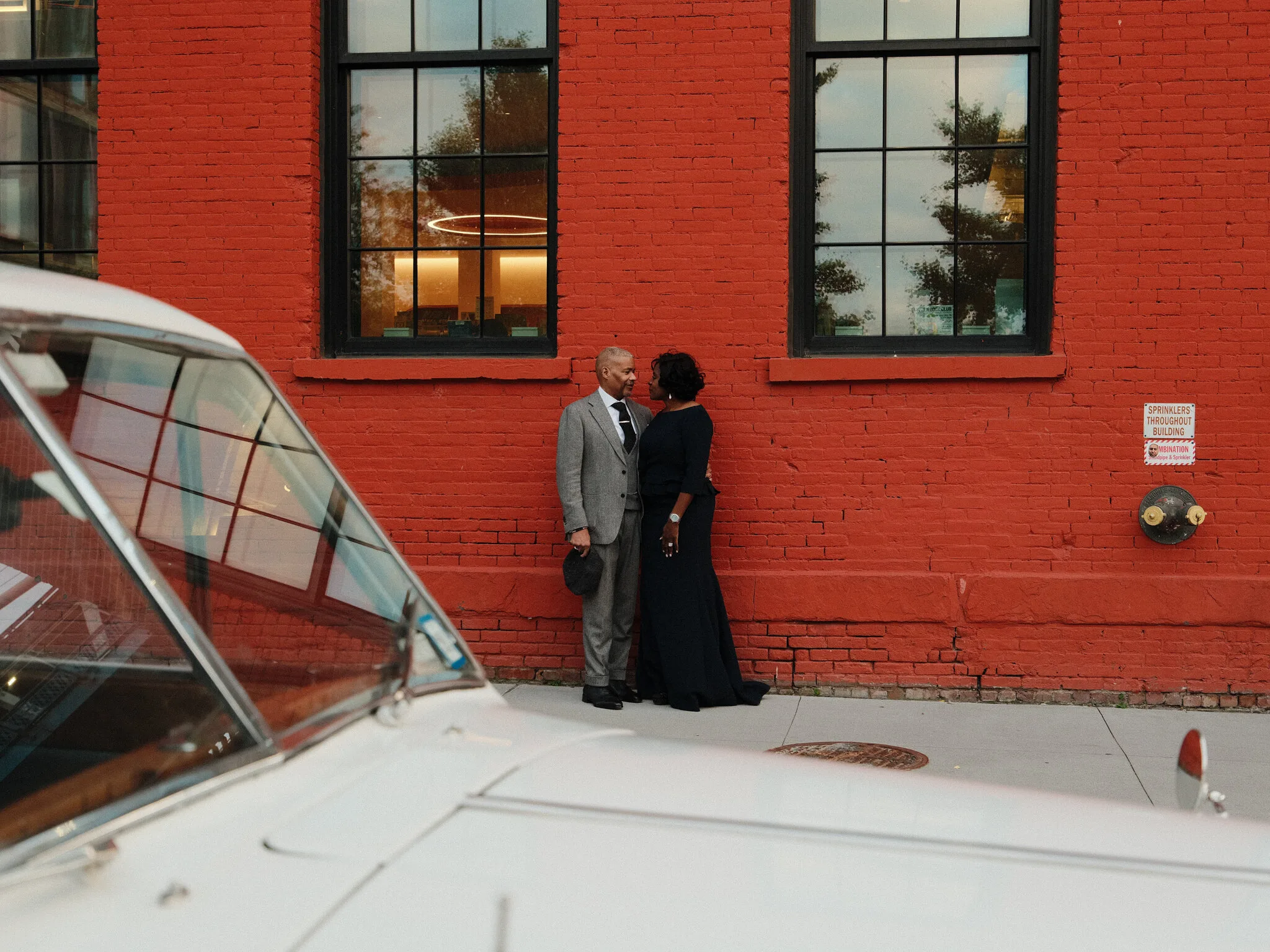 Marc and Olgeta holding hands walking across the Brooklyn Bridge into the dusk, city lights emerging.