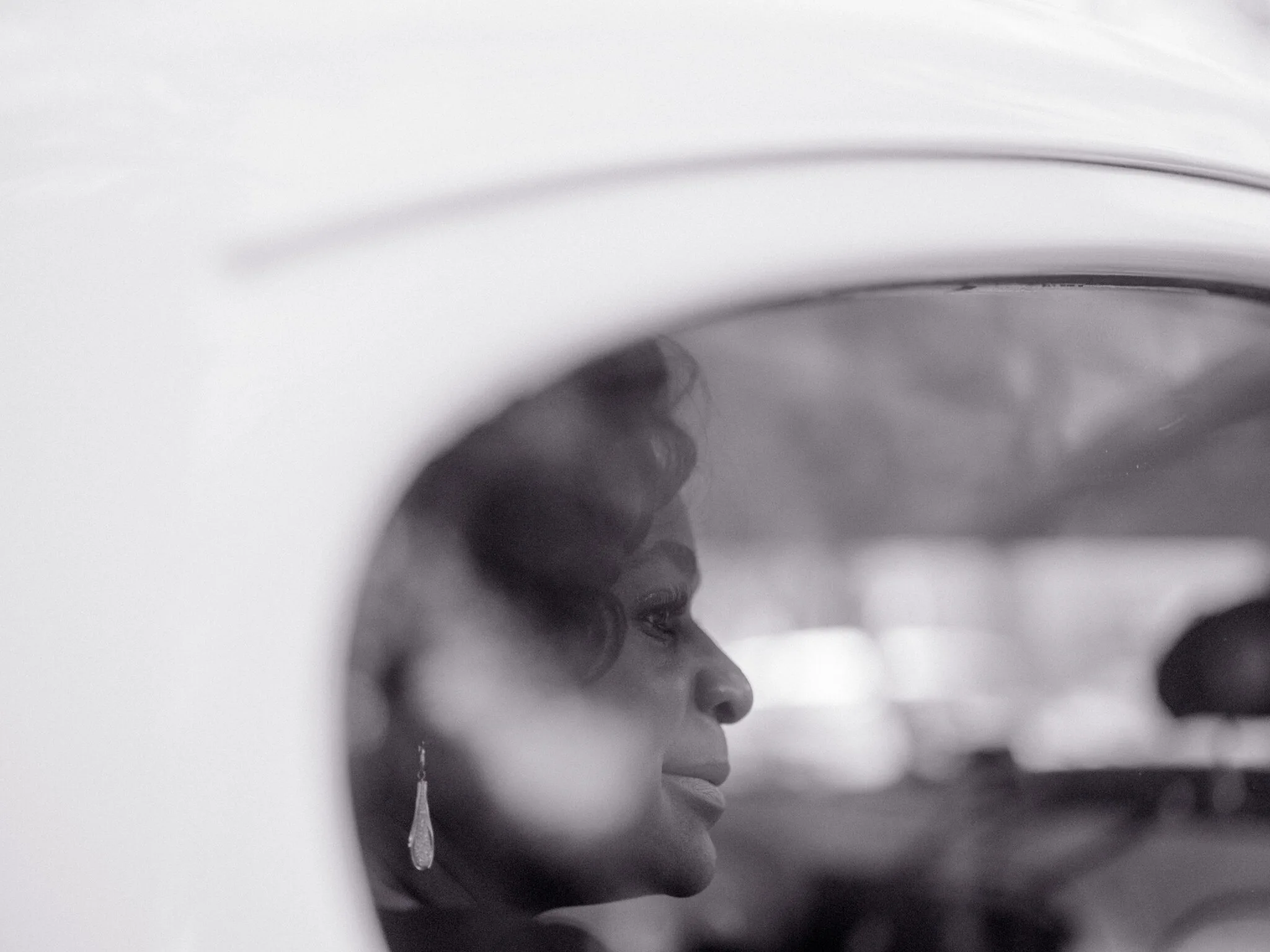 Olgeta reflected in the car mirror, soft evening light on her face.