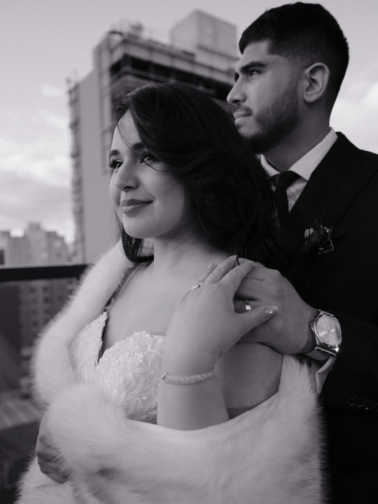 Couple embracing beneath the Manhattan Bridge with New York City skyline at dusk