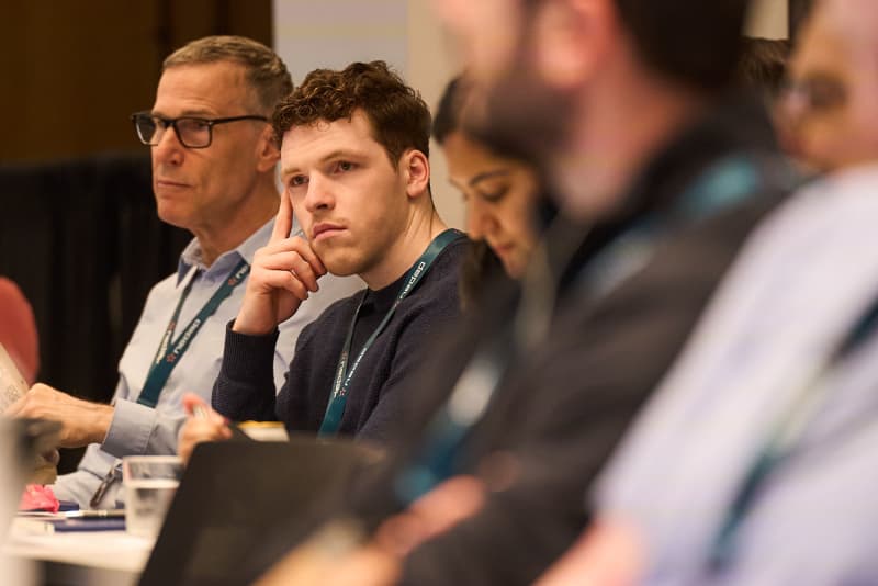 Attendee in conversation at a corporate networking event in NYC, badge lanyard visible — Core Visuals event photography