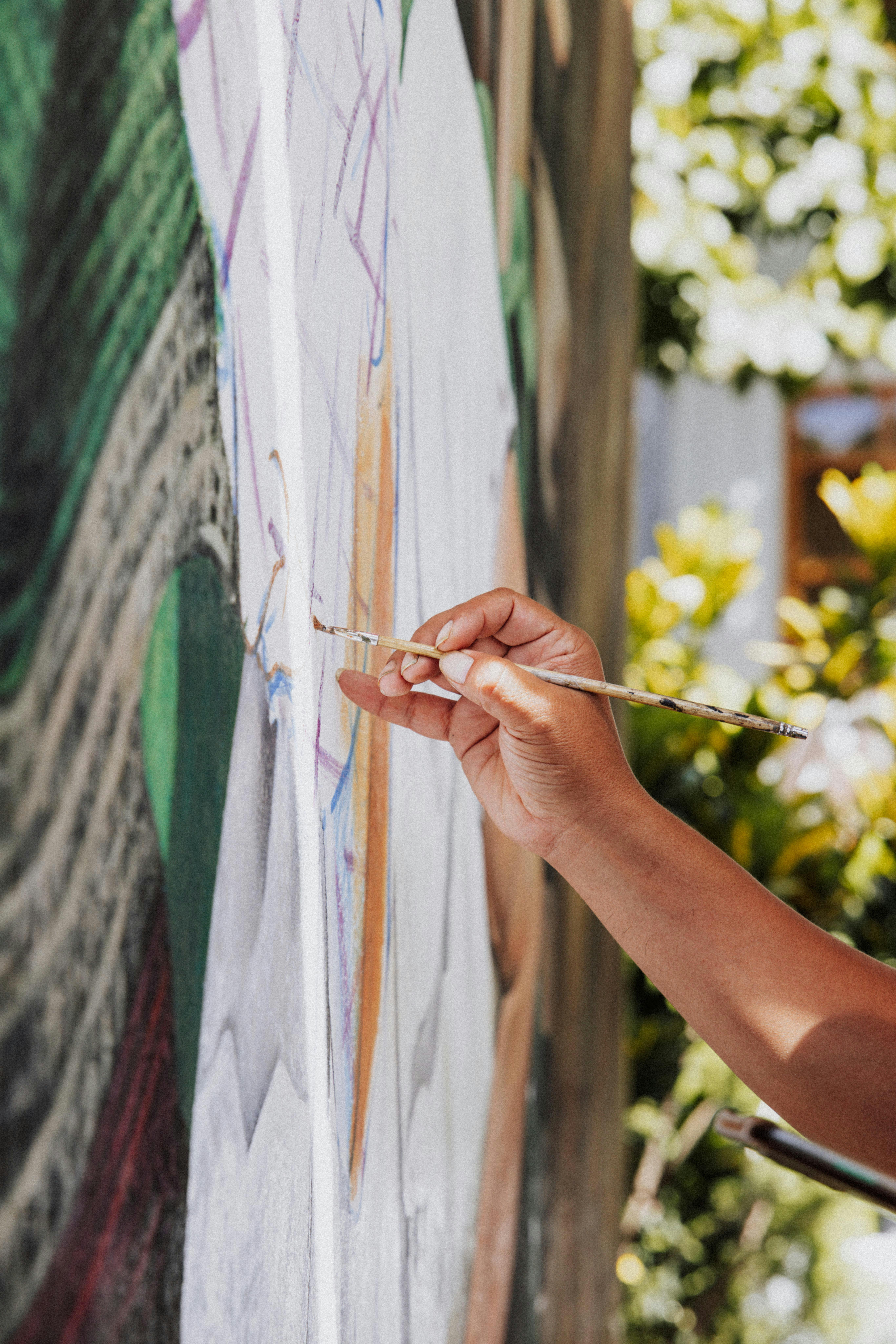 Close-up of hand holding brush painting detailed artwork showing artistic process