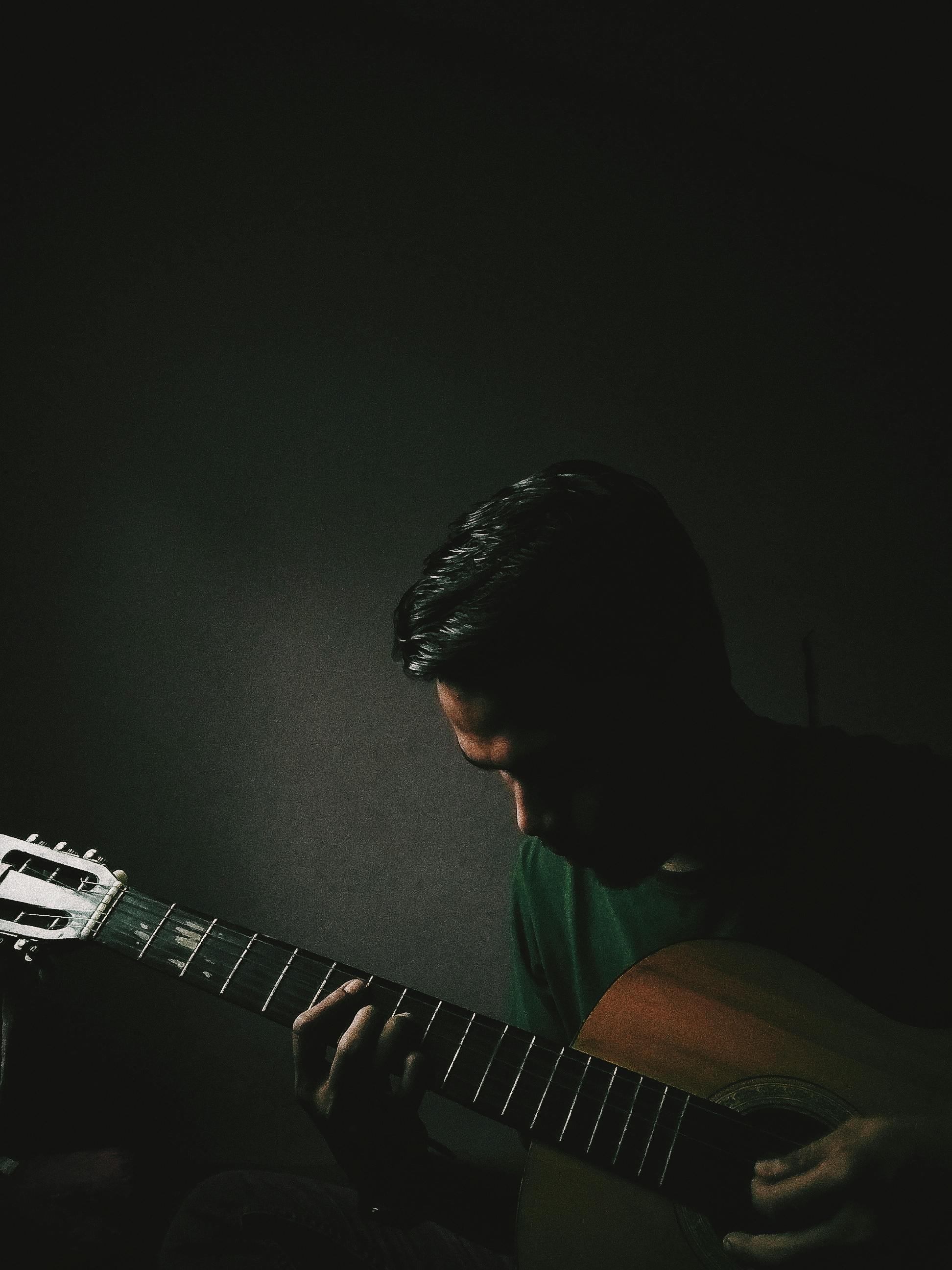 Musician playing acoustic guitar in low light close-up demonstrating intimate branding photography