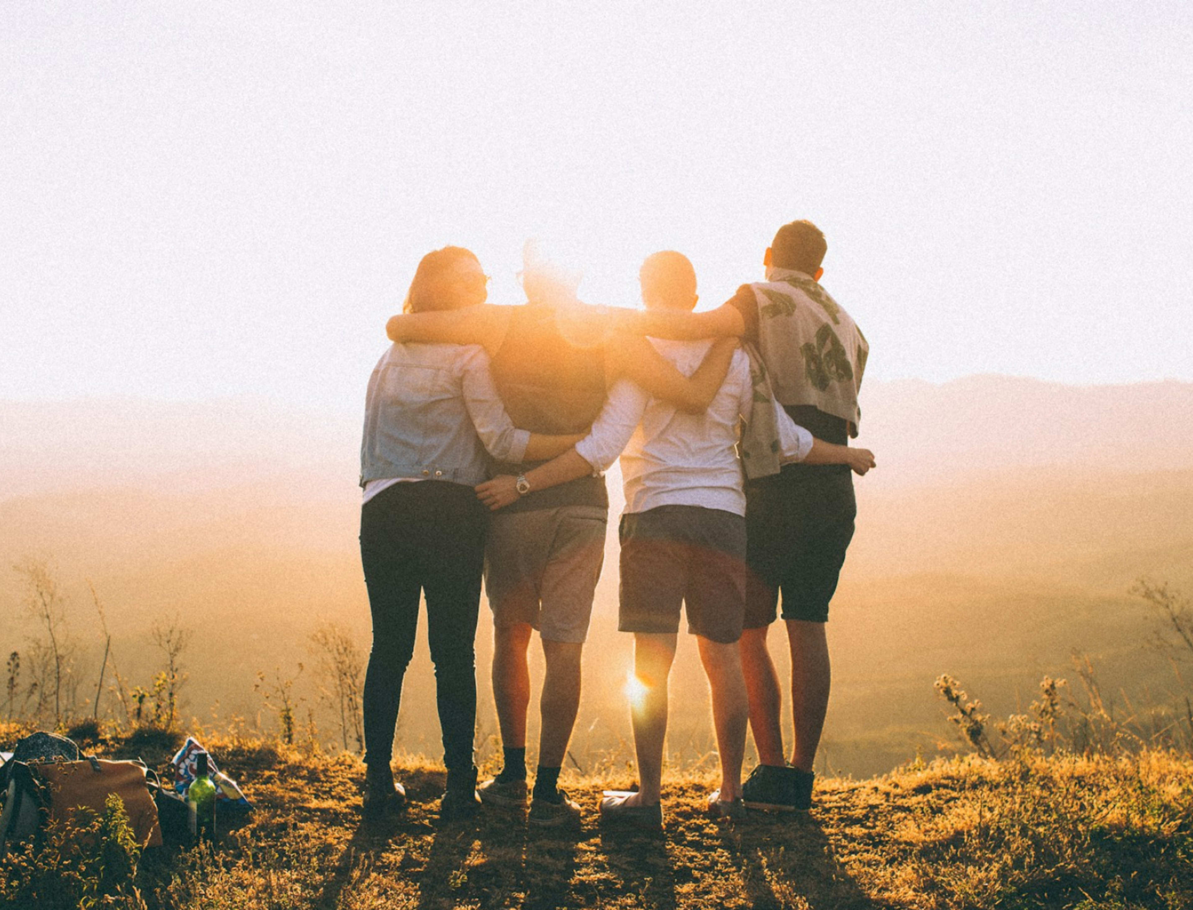 Junge Menschen halten sich in den Armen und betrachten den Sonnenaufgang