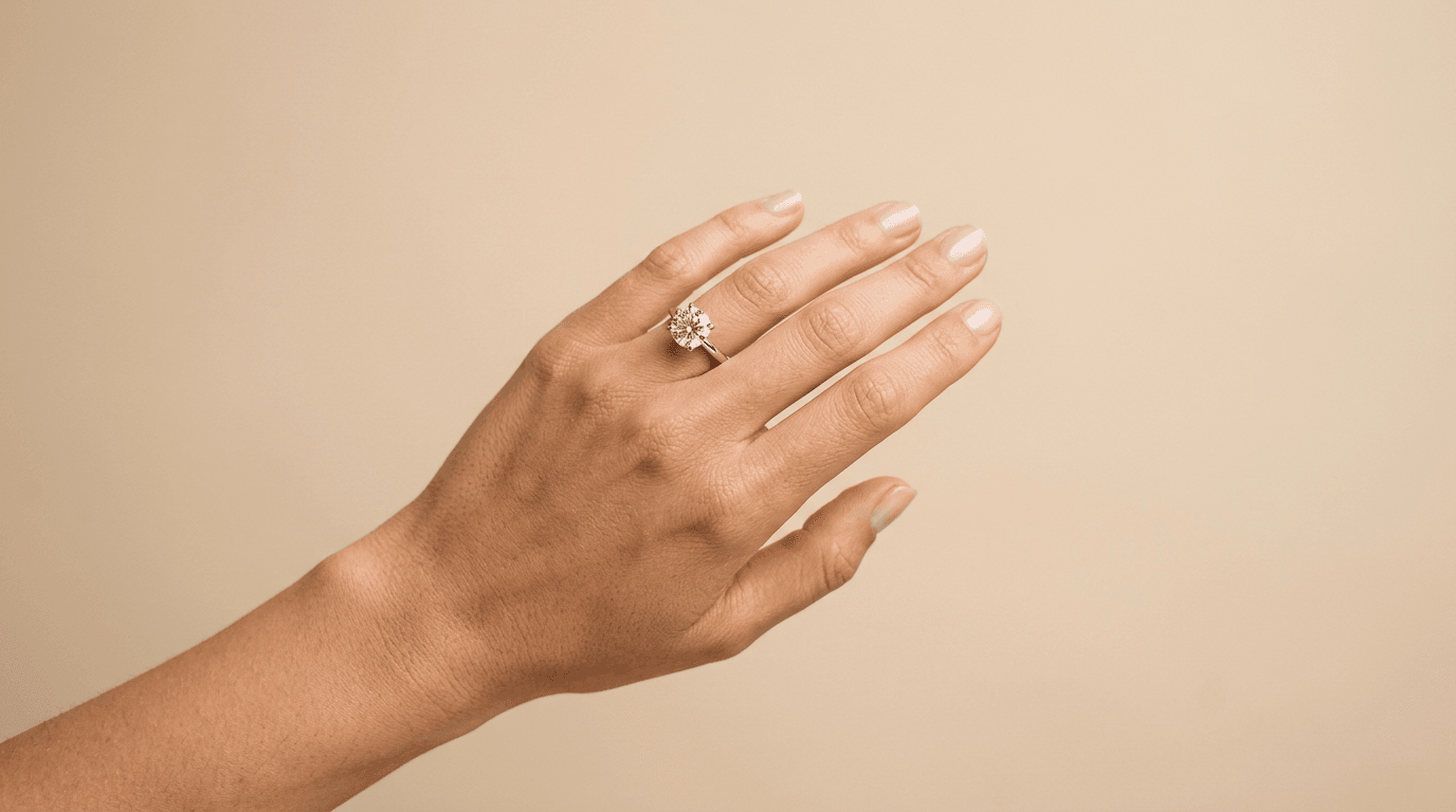 Hero image, a hand wearing a solitaire engagement ring, bright commercial ecommerce studio still