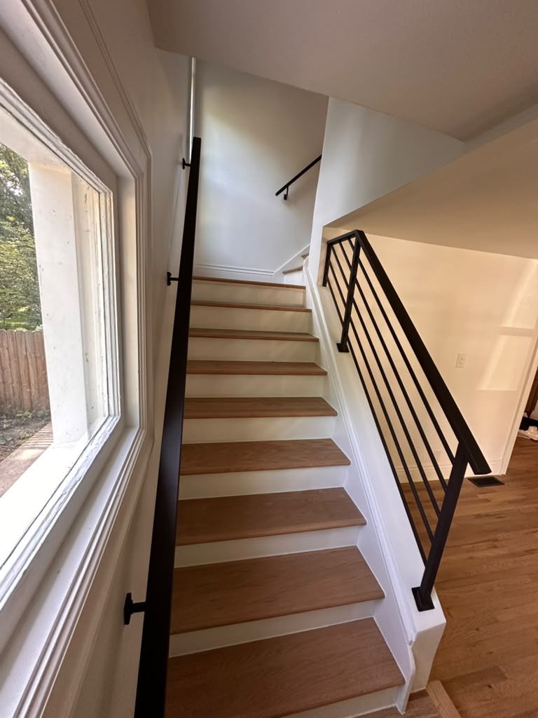 Custom black metal stair railing with horizontal bars and wall-mounted handrail installed by Hot Fab Welding in Warren, MI