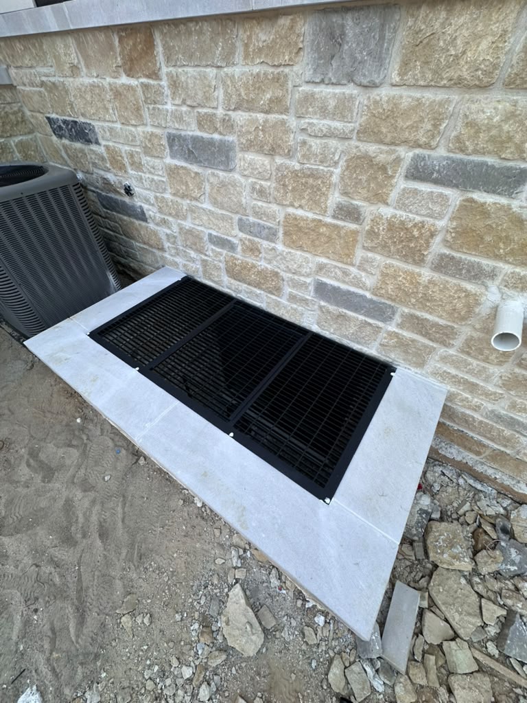 Custom black steel window well grate installed over an egress window on a stone home in Warren, MI