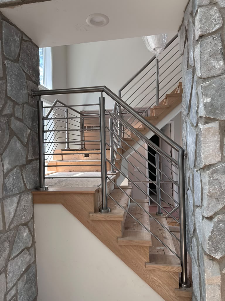 Brushed stainless steel stair railing framed by a natural stone entryway in a custom Michigan home