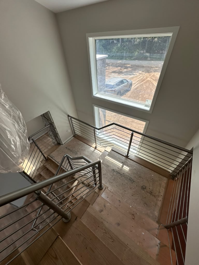 Modern horizontal bar stair railing in brushed stainless steel viewed from the upper landing of a Michigan home