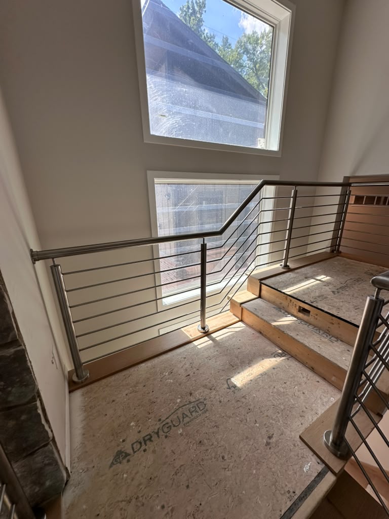 Stair landing with a horizontal rod stainless steel railing beside tall windows in Warren, MI
