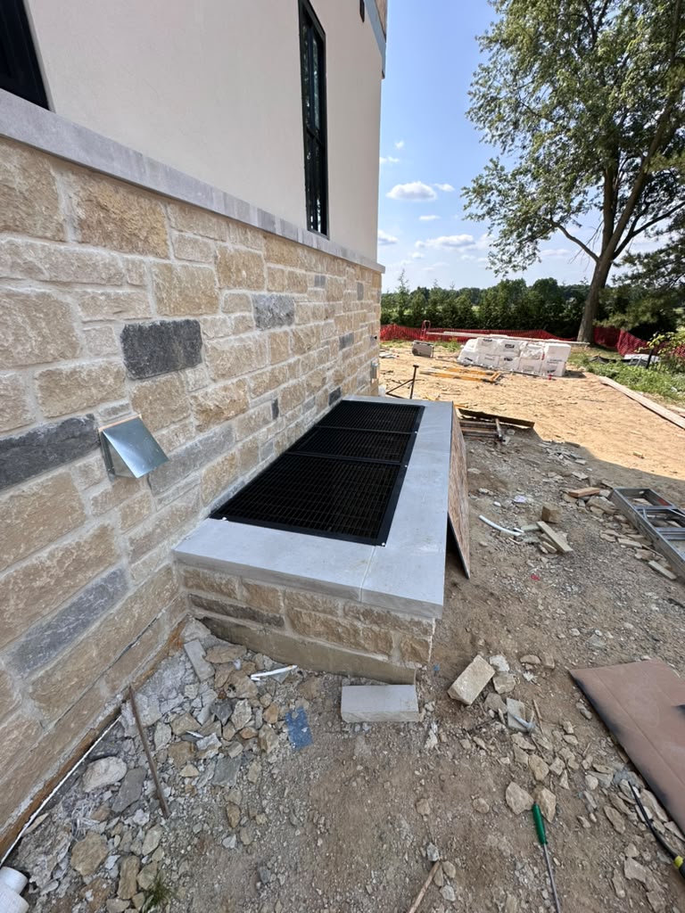 Black steel egress window well cover custom fabricated for a new stone home in Metro Detroit