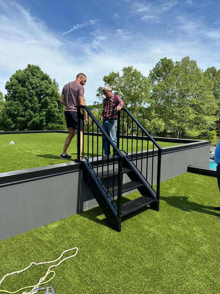Black steel exterior staircase with perforated metal treads leading to a raised patio, custom built by Hot Fab Welding in Metro Detroit
