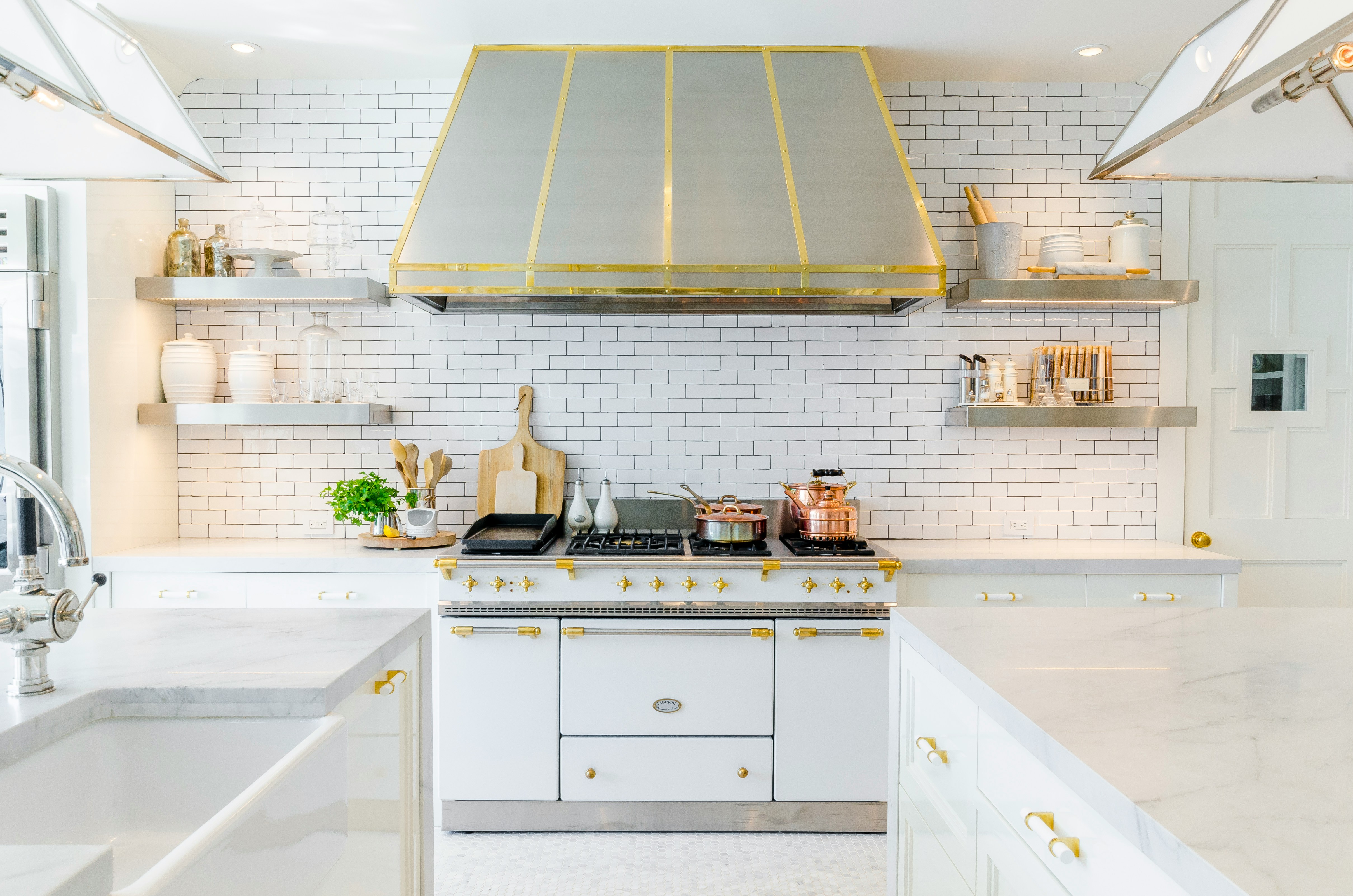 White Kitchen with Marble Countertops and Brass Range Hood