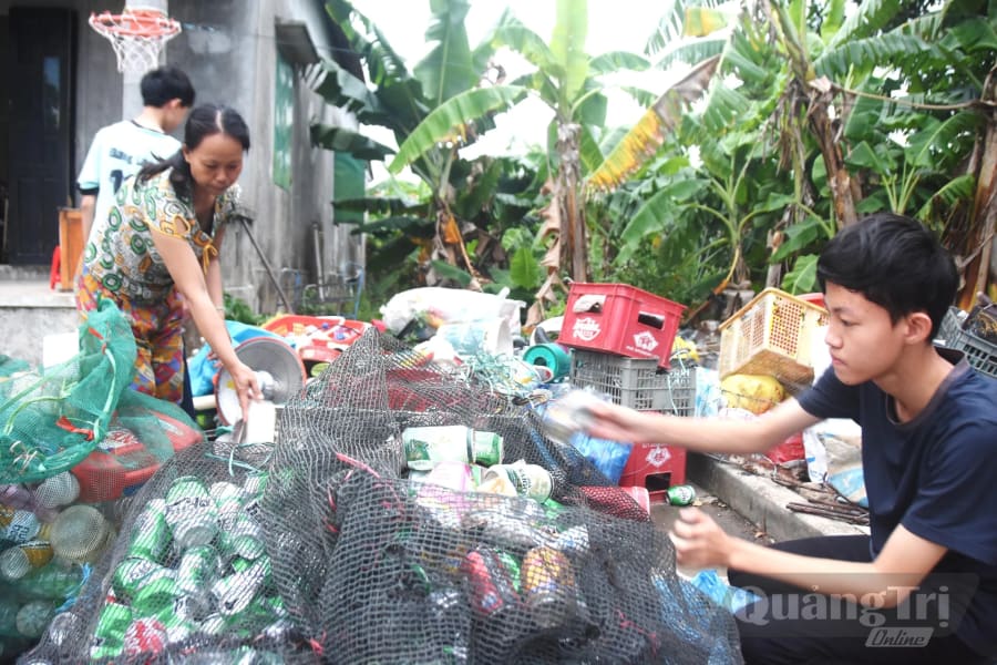 
Em Đoàn Đăng Việt phụ giúp mẹ phân loại ve chai - Ảnh: Đ.V