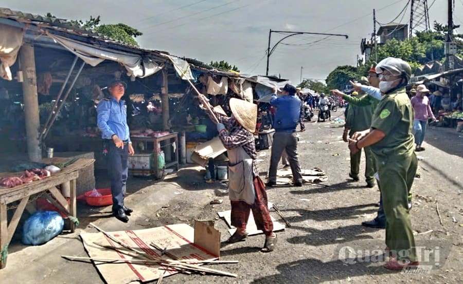 Lực lượng chức năng phường Quảng Trị hỗ trợ người dân di dời bạt che, bàn ghế lấn chiếm vỉa hè - Ảnh: K.S