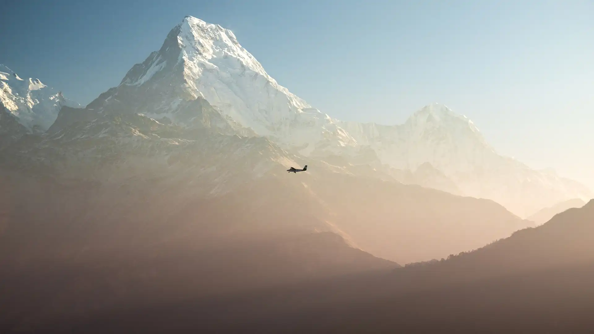Small plane flying past snow-covered Himalayan peaks above hazy mountain valleys.