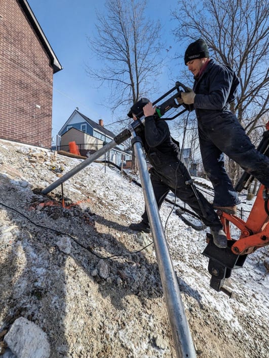 Installer operating helical pile equipment in field conditions