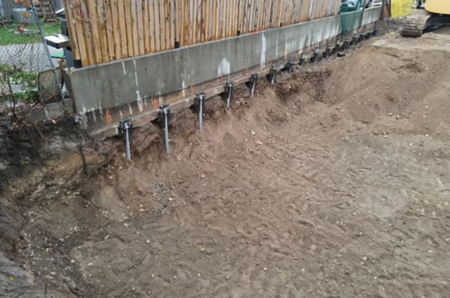 Row of helical piles supporting a retaining wall