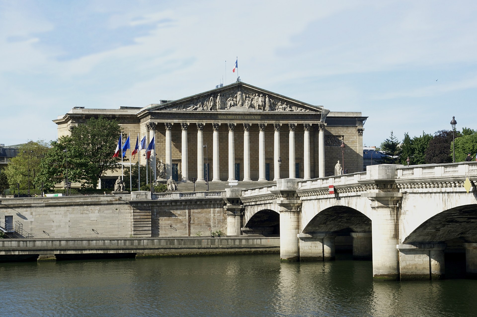 The French National Assembly building in Paris, with the Pont de la Concorde and Seine River in the foreground.