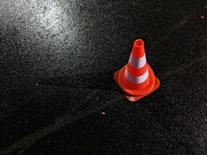 Traffic safety cone on wet road representing rental car safety and insurance protection