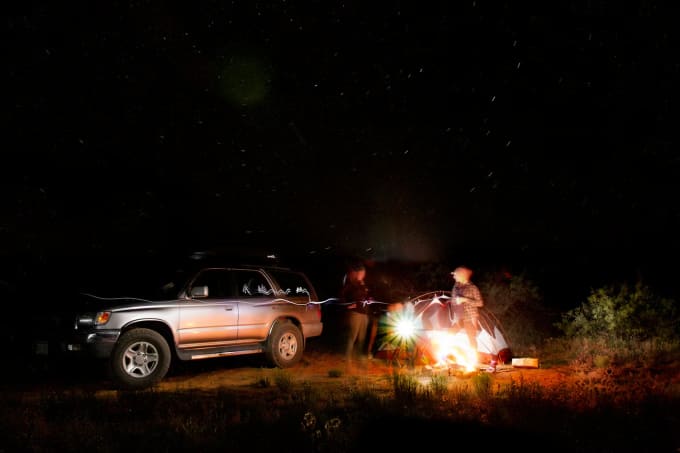 SUV parked next to campfire under starry desert sky on a Sedona road trip