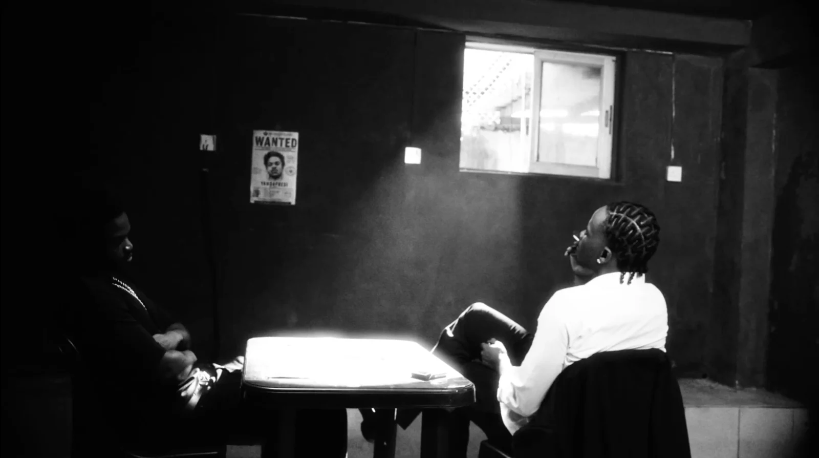 A black-and-white scene around a table in The Associate