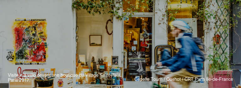 Visiteur à vélo devant une boutique du Village Saint-Paul, Paris 2017. Capelle Tourn / Ooshot / CRT Paris Ile-de-France