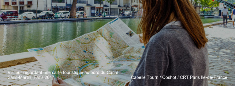 Visiteur regardant une carte touristique au bord du Canal Saint-Martin, Paris 2017. Capelle Tourn / Ooshot / CRT Paris Ile-de-France