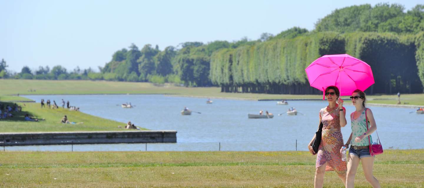 Domaine de Versailles, les Jardins et le Grand Canal, visiteurs avec parapluie rose.