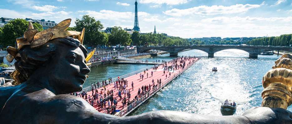 Running track on the Seine seen from a bridge with a statue in the foreground and the Eiffel Tower, Paris