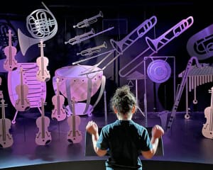 Enfant jouant les chefs d'orchestre devant des instrument à la philharmonie des enfants, Paris