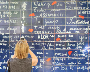 Visiteur photographiant avec son smartphone le Mur des Je T'aime