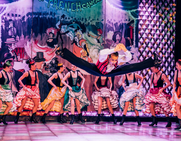 A male and female dancers performing a French Cancan on stage