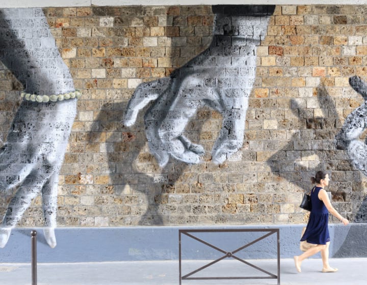 Légende Femme passant devant une oeuvre Street Art de Oji, rue de l&#039;Ourcq, Paris