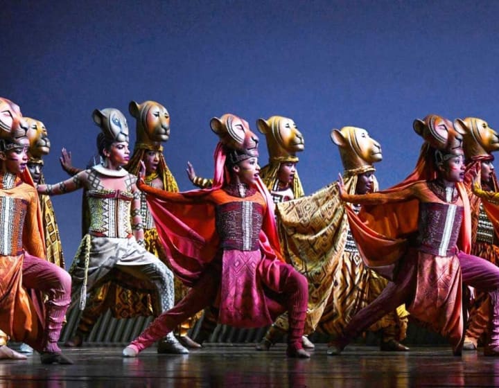 Acteurs en représentation de la pièce de théâtre du Roi Lion avec des costumes de lions.