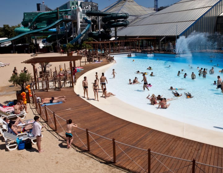 Espace de plein air à Aquaboulevard avec piscine, fontaine, espace de détente et toboggans.