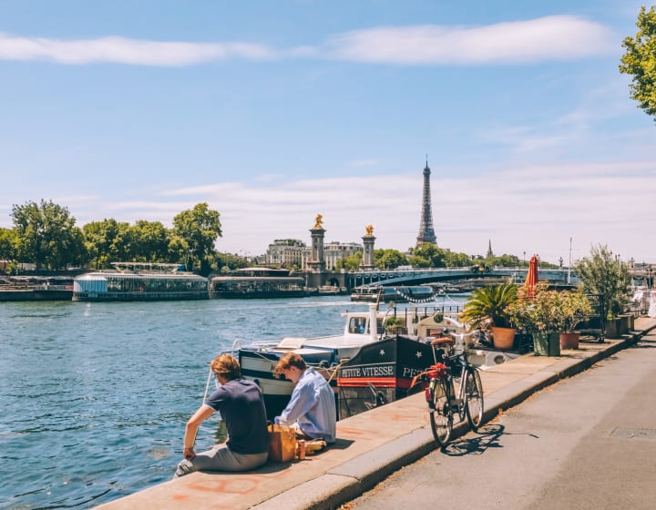 Deux jeunes hommes assis sur les berges de la Sine avec péniches, pont Alexandre III et Tour Eiffel