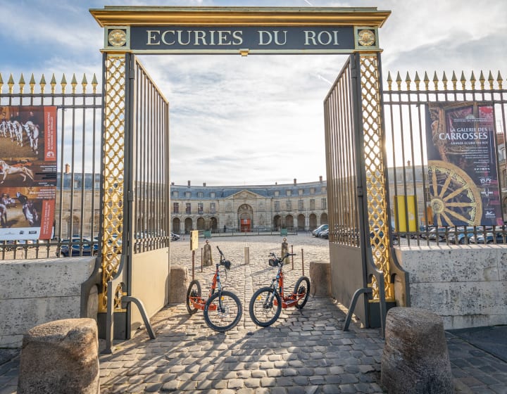 Trottinettes électriques tout terrain devant l&#039;entrée des écuries du roi au château de Versailles