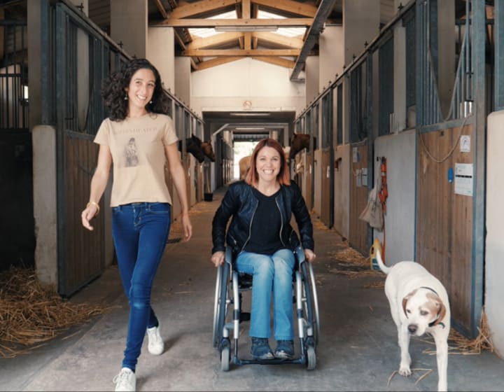 Smiling woman in a wheelchair in the middle of stables