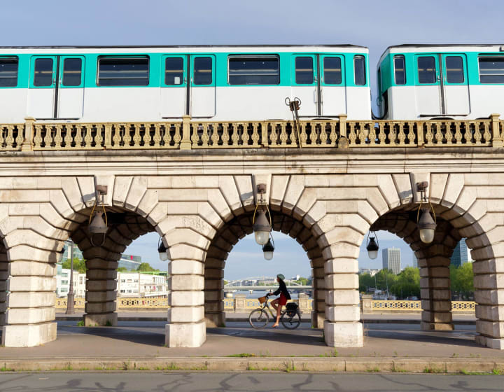 Cyclist riding under a bridge with an overhead metro on top