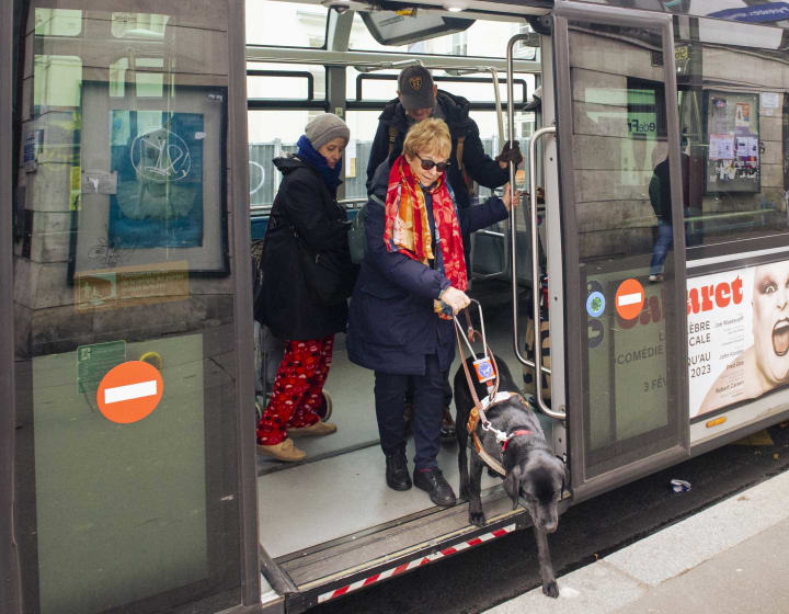 Woman and her guide dog getting out of a bus in Paris