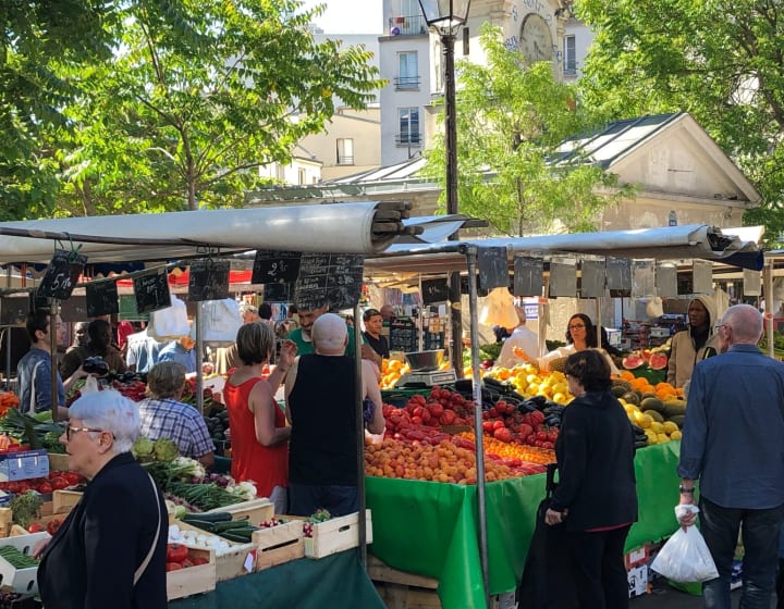 Clients et marchands autour des étals de fruits et de légumes au marché d'Aligre